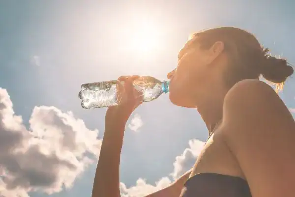 Hydration: The Secret Ingredient for a Toned Stomach and Enhanced Fitness 3 Image of woman drinking water to hydrate Shoreham Beach after run.