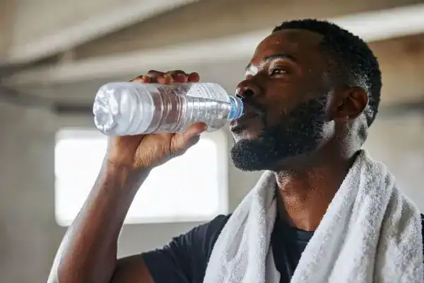 Hydration: The Secret Ingredient for a Toned Stomach and Enhanced Fitness 1 Image of man drinking water to improve hydration Shoreham Beach after work out.
